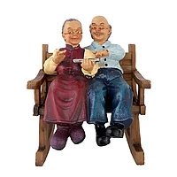 Decoratiune din rasina reprezentand un bunic si o bunica stand pe un balansoar cu o tableta, 14 cm